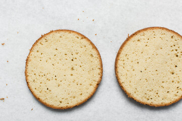 Overhead view of vanilla cake layers on a white countertop, top view of vanilla cake slices about to be assembled, process of making layered cake