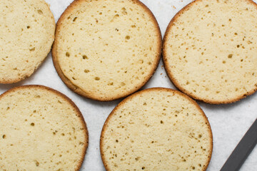 Overhead view of vanilla cake layers on a white countertop, top view of vanilla cake slices about to be assembled, process of making layered cake