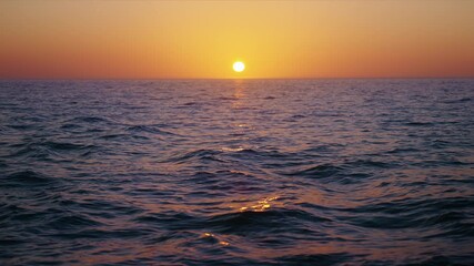 Experience a serene slowmotion sunset over the vast ocean, where vibrant colors reflect on gentle waves. This tranquil scene invites relaxation and inspires appreciation of natures beauty