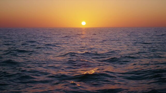 Experience a serene slowmotion sunset over the vast ocean, where vibrant colors reflect on gentle waves. This tranquil scene invites relaxation and inspires appreciation of natures beauty