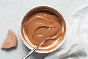 Overhead view of nigerian akamu being made in a white bowl, pap akamu or ogi in a white bowl, top view of nigerian guinea corn pudding in a white ramekin