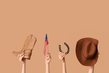Female hands with cowboy shoe, hat, horseshoe and flag of USA on color background