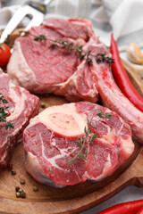 Pieces of raw beef and spices on light grey table, closeup