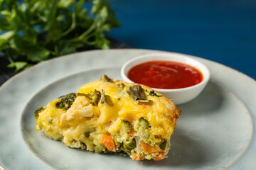 Piece of tasty vegetable casserole and sauce on blue table, closeup