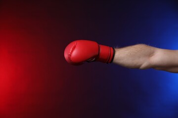 Man with boxing glove fighting on dark background in neon lights, closeup. Space for text