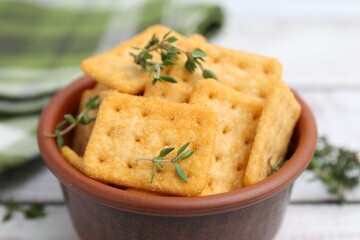 Tasty salty crackers with thyme on white wooden table, closeup