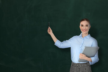 Teacher pointing at green chalkboard, space for text