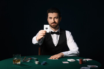 Handsome male banker with poker chips and playing cards at table in casino