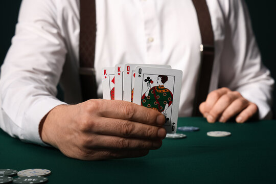 Male banker with poker chips and playing cards at table in casino, closeup