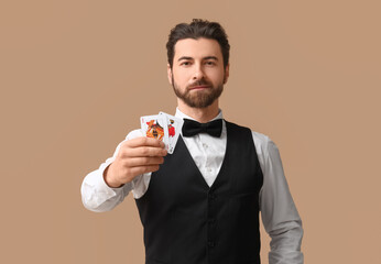 Handsome male banker with playing cards for poker on beige background
