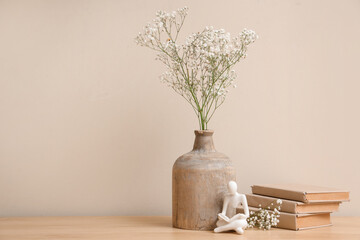 Gypsophila flowers in vase, human figure and books on table in living room. Closeup