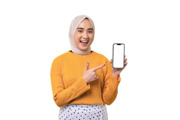 Beautiful cheerful Asian girl wearing hijab pointing index finger at mobile phone with blank white screen isolated on transparent background, mockup, copy space