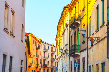 Warm sunlight bathes a charming Italian street lined with colorful historic buildings and balconies. A peaceful, vibrant atmosphere perfect for travel, architecture, or lifestyle themes