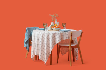 Restaurant table for two with plates, fruits and flowers on orange background