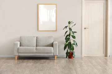 Interior of living room with grey sofa, plant and blank frame