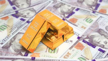 gold bullion glistens on top of a stack of US dollar bills. gold investment concept