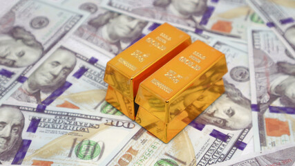 gold bullion glistens on top of a stack of US dollar bills. gold investment concept