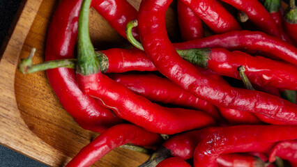 Top view of a pile of fresh red chilies with natural green stems on a wooden tray. Suitable for cooking or culinary articles