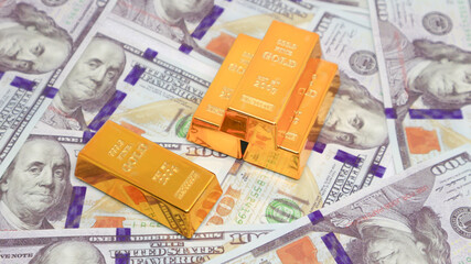 gold bullion glistens on top of a stack of US dollar bills. gold investment concept
