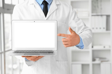 Male doctor pointing at blank laptop in clinic, closeup