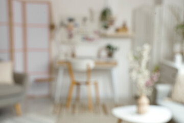 Blurred view of light office with workplace, pegboard and blossoming branches in vases