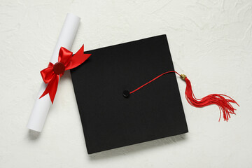 Graduation hat and diploma on white background, top view