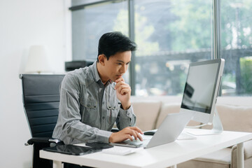 Obraz premium Young businessman working with working notepad, tablet and laptop documents talking