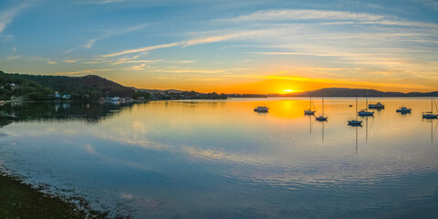 Sunrise with high cloud, boats and reflections over the water © Merrillie