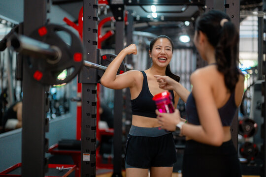 Two young women showing muscles and having fun at the gym