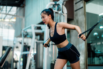 Asian sportswoman exercising with cable machine in gym