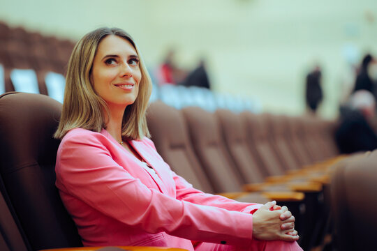Woman in Elegant Suit Sits in a Conference Room and Waits. Entrepreneur waiting to attend a seminar in a large event hall 
