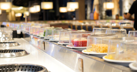 Plates with various sushi dishes are moving on a conveyor belt in a modern sushi restaurant, offering a convenient and visually appealing dining experience