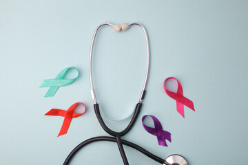 Stethoscope Surrounded By Colorful Awareness Ribbon On Light Blue Background. World Cancer Day.
