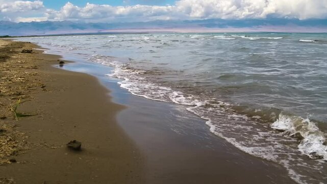 This footage captures the waves rolling towards the beach of Assyk Kul Lake in Kyrgyzstan, offering a soothing view of the water's movement.
