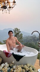 Handsome Man Relaxing in a Bubble Bath with a Stunning Mountain Sunset View
