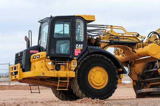 ide view of a Caterpillar 623H wheel tractor-scraper at a construction site, showing hydraulic systems and large tires used in heavy-duty earthmoving and grading for land development projects