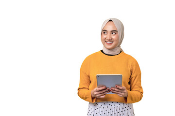 Beautiful smiling happy Asian girl wearing hijab holding digital tablet and looking aside at copy space isolated on transparent background