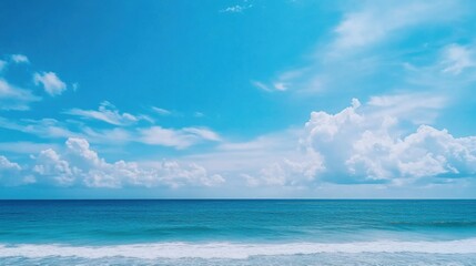 Obraz premium Serenity of the Ocean Under a Clear Blue Sky with Fluffy Clouds