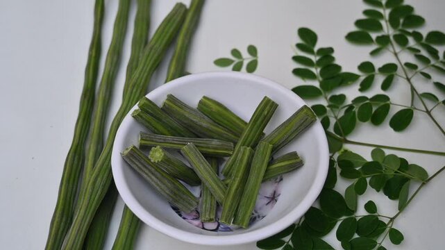 Moringa oleifera or drumstick pods on white background. This is a Moringaceae family tree. Its other names &nbsp;moringa, horseradish, and&nbsp;ben oil&nbsp;tree and&nbsp;benzolive. It is a popular vegetable. Slow motion