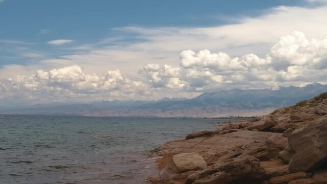 Assyk Kul Lake, located in Kyrgyzstan, features rocky shorelines and clear waters, offering a stunning natural environment perfect for outdoor exploration and photography.