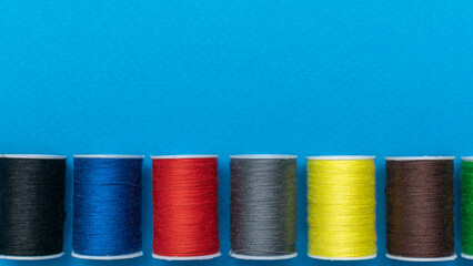 Colorful Thread Spools on Blue Background: Vibrant Textile Essentials for Sewing and Crafting