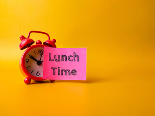 Red alarm clock with sticky note with the word Lunch Time on a yellow background