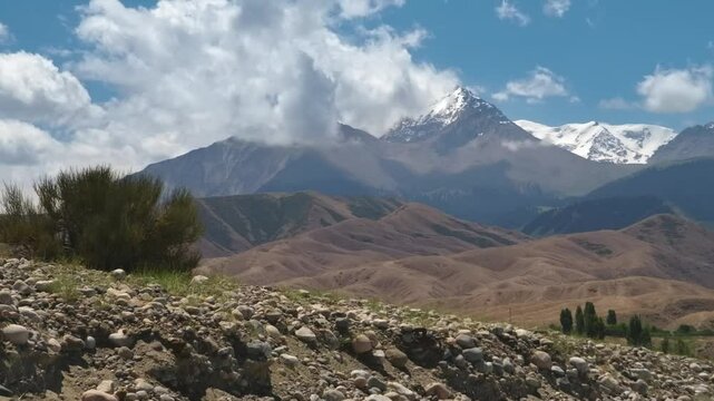 This time-lapse footage shows the beauty of clouds moving across the sky over the majestic mountains near Assyk Kul Lake in Kyrgyzstan, creating a dynamic natural scene.