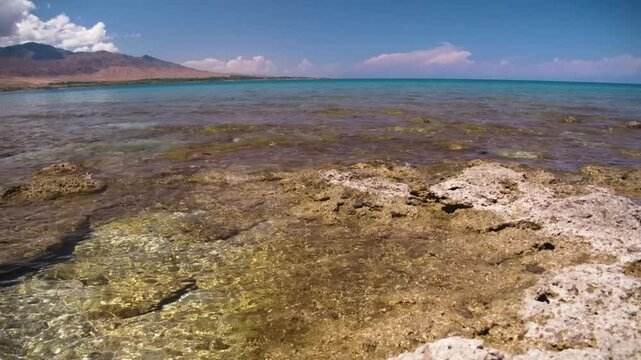 This footage showcases Assyk Kul Lake&rsquo;s rocky beach bed with crystal-clear turquoise water, offering a stunning natural scene surrounded by the beauty of Kyrgyzstan.
