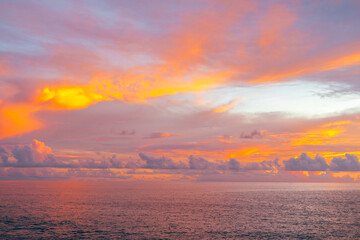 Sunset over sea with dramatic orange sky and soft twilight glow on the waves.