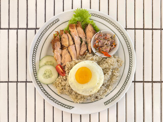 Close up of chopped roaster chicken with limau rice or lime rice, topped with sunny sided egg and sambal matah. Sambal matah is a stir fried onion native to Indonesia. Chicken food photography.