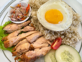 Close up of chopped roaster chicken with limau rice or lime rice, topped with sunny sided egg and sambal matah. Sambal matah is a stir fried onion native to Indonesia. Chicken food photography.