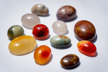 A collection of polished gemstones displays a variety of colors, textures, and unique patterns under soft light.