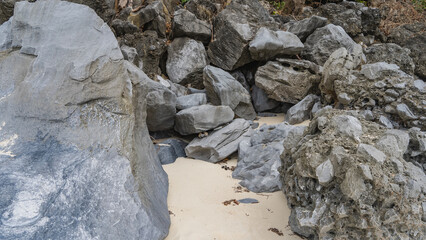 A pile of picturesque boulders on a secluded tropical beach. Fallen dry leaves on untouched sand. Philippines. Palawan. Close-up
