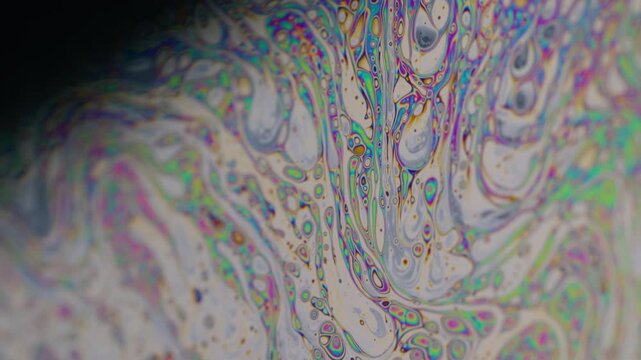 Paint mix. Spot gasoline. Defocused multicolor purple green liquid oil curve acrylic slick on dark black blurred light abstract art background.